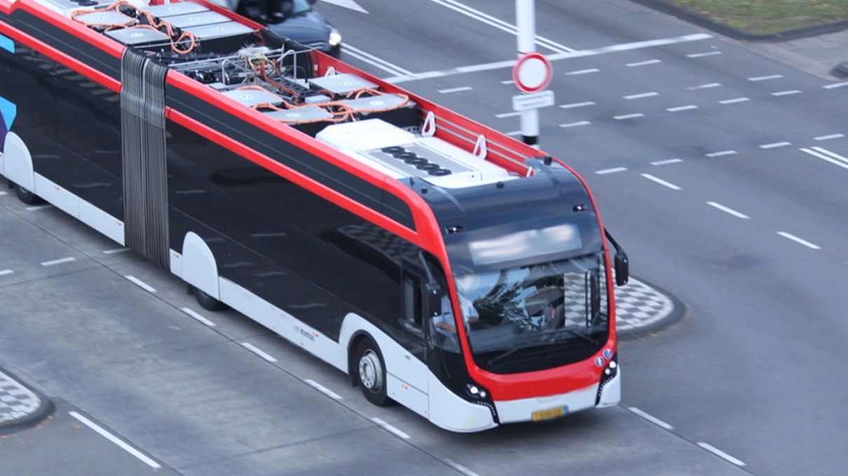 A red and white bus drives along a street.