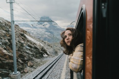 Eine Frau schaut aus einem Zugfenster heraus.